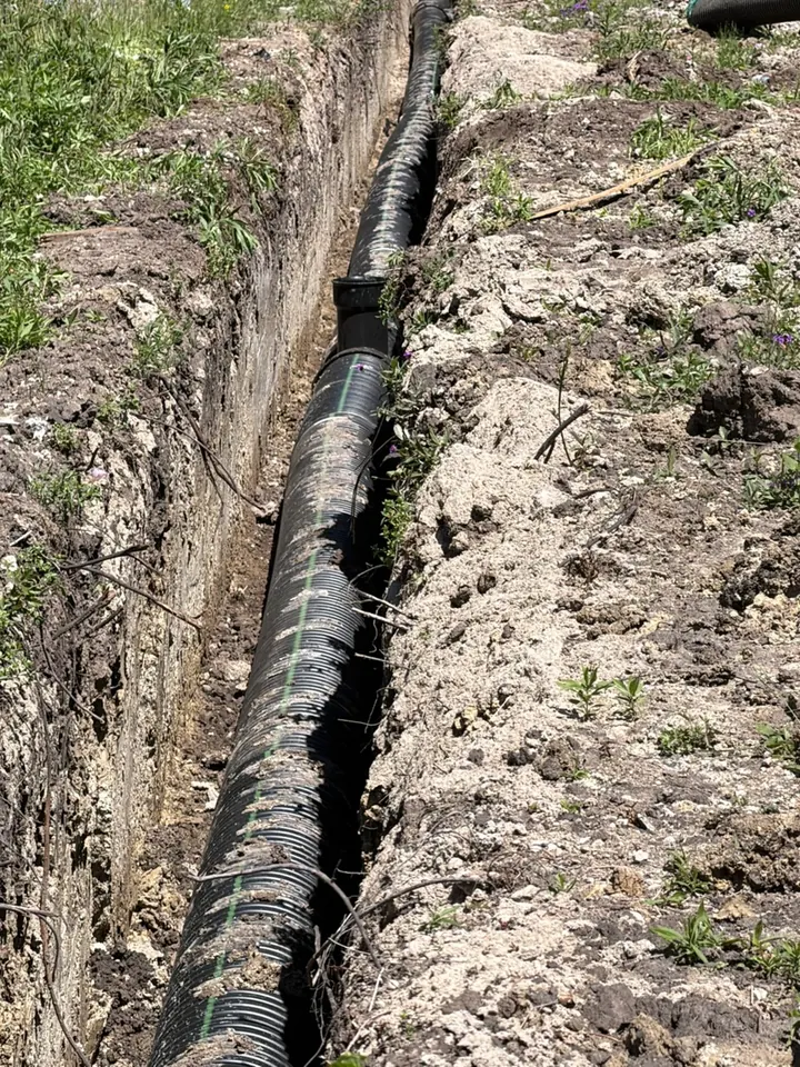 A corrugated drainage line with an upright riser in a dug trench